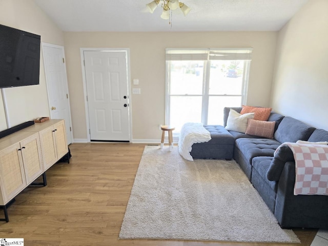 living area featuring light wood finished floors, a ceiling fan, and baseboards