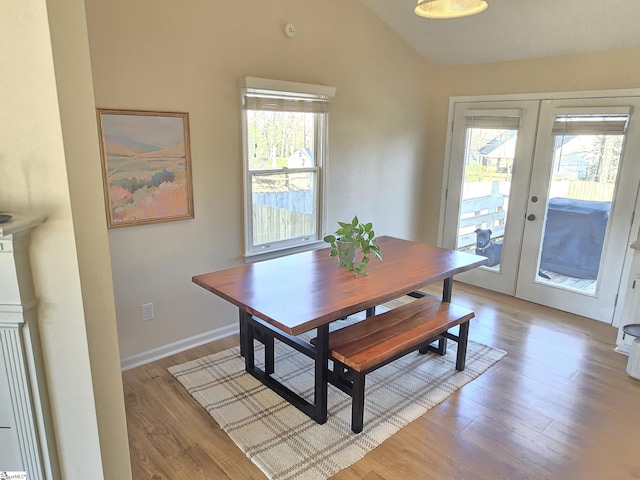 dining space with vaulted ceiling, french doors, light wood-type flooring, and a healthy amount of sunlight