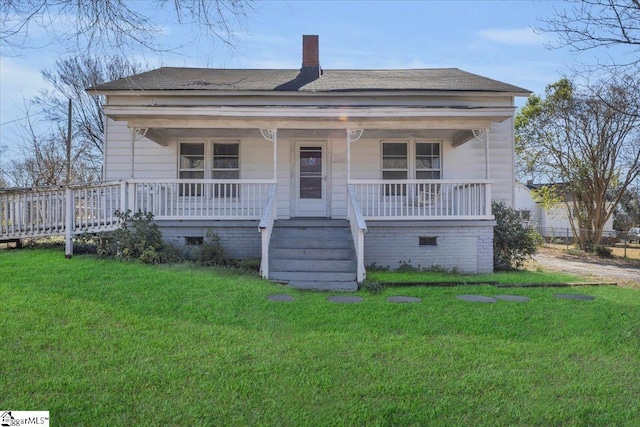 view of front facade featuring crawl space, a chimney, a porch, and a front lawn