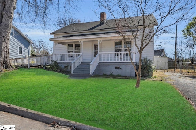 view of front of property featuring a porch, fence, a front lawn, and a chimney