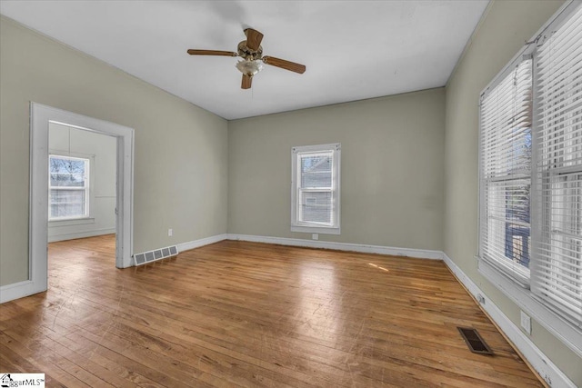 empty room featuring visible vents, baseboards, and hardwood / wood-style floors