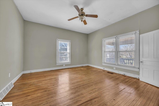 unfurnished room featuring ceiling fan, visible vents, baseboards, and hardwood / wood-style floors