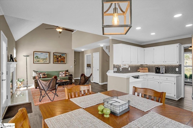 dining area with vaulted ceiling, a fireplace with raised hearth, dark wood-style flooring, and ceiling fan