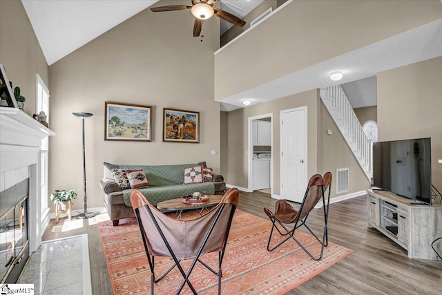 living area with visible vents, wood finished floors, stairs, and a tiled fireplace