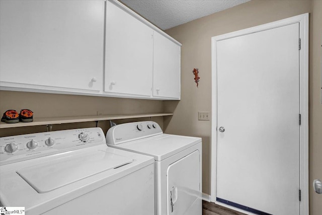 washroom featuring washer and dryer, cabinet space, and a textured ceiling