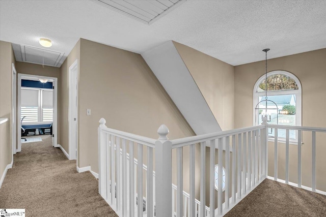 hall with baseboards, carpet, attic access, and a textured ceiling