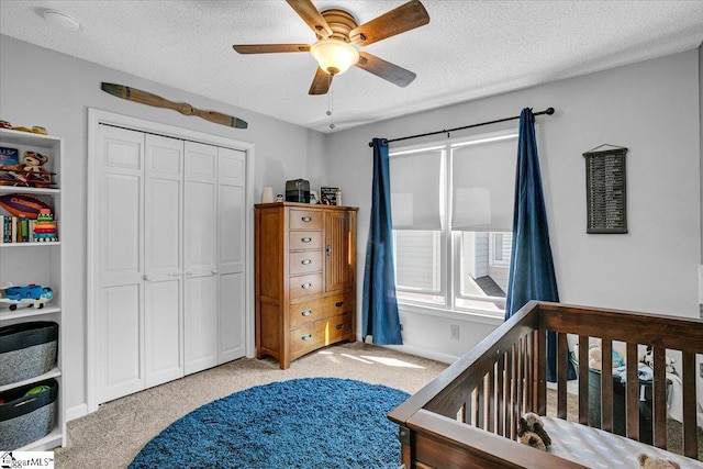 bedroom featuring a closet, light carpet, a textured ceiling, and a ceiling fan