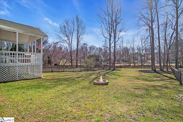 view of yard featuring an outdoor fire pit, a deck, and fence