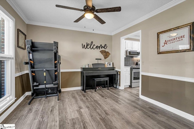 interior space with a ceiling fan, crown molding, baseboards, and wood finished floors