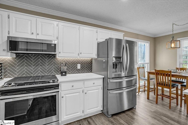 kitchen with light countertops, crown molding, wood finished floors, and appliances with stainless steel finishes