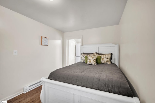 bedroom with baseboard heating, baseboards, and wood finished floors