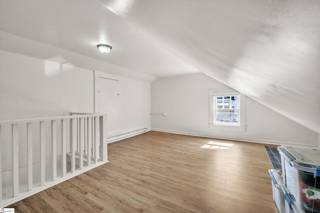 additional living space with vaulted ceiling, wood finished floors, and a baseboard radiator