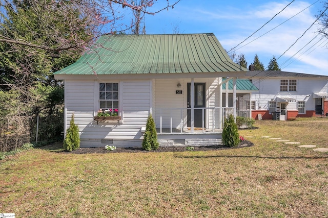 rear view of house featuring covered porch, metal roof, and a yard