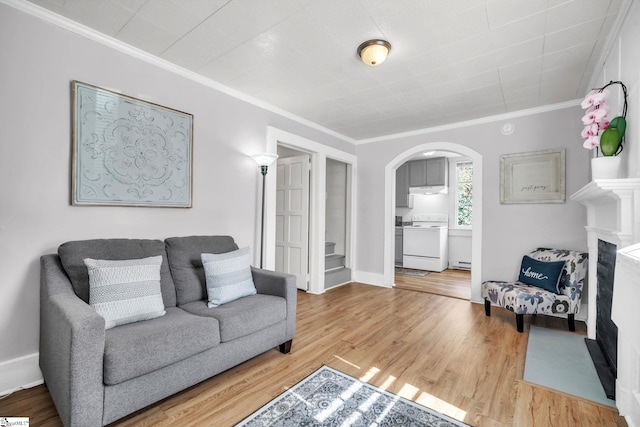 living room featuring arched walkways, crown molding, baseboards, and wood finished floors