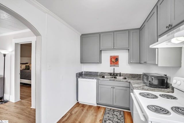 kitchen featuring gray cabinets, a sink, under cabinet range hood, white appliances, and crown molding