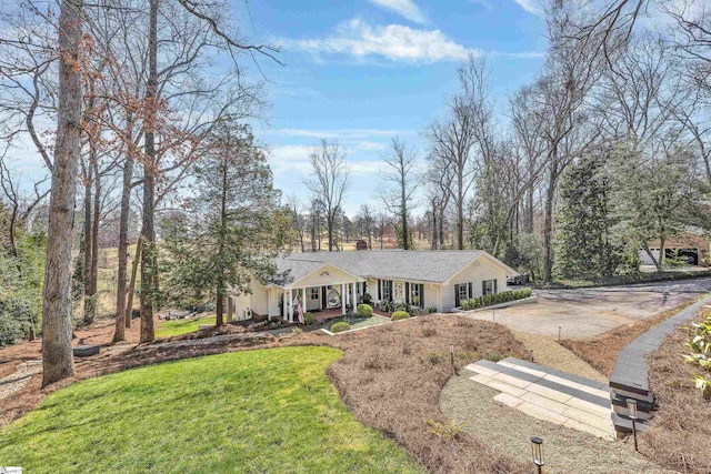 ranch-style house with a chimney, a porch, concrete driveway, and a front lawn