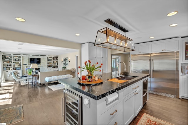 kitchen featuring a sink, dark wood-type flooring, wine cooler, built in refrigerator, and open floor plan