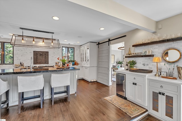 kitchen with a barn door, refrigerator, dark wood-style floors, and a wealth of natural light