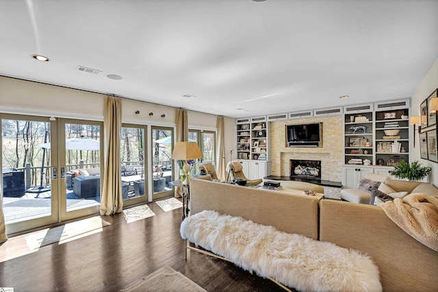 living room with visible vents, built in features, dark wood finished floors, french doors, and a fireplace