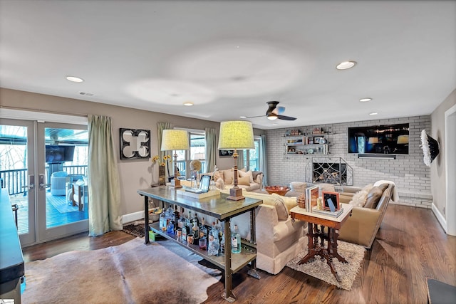 living room featuring visible vents, wood finished floors, recessed lighting, brick wall, and a fireplace