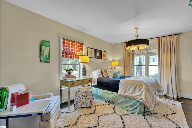 bedroom featuring a notable chandelier, baseboards, and wood finished floors