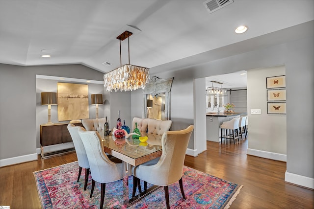 dining room with visible vents, a notable chandelier, wood finished floors, baseboards, and lofted ceiling