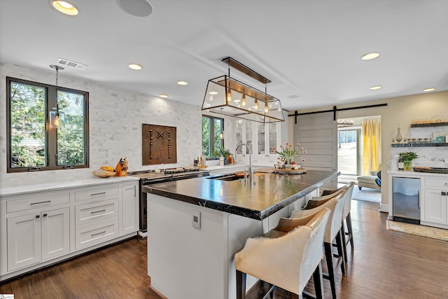 kitchen with a sink, range with electric stovetop, a kitchen bar, a barn door, and tasteful backsplash