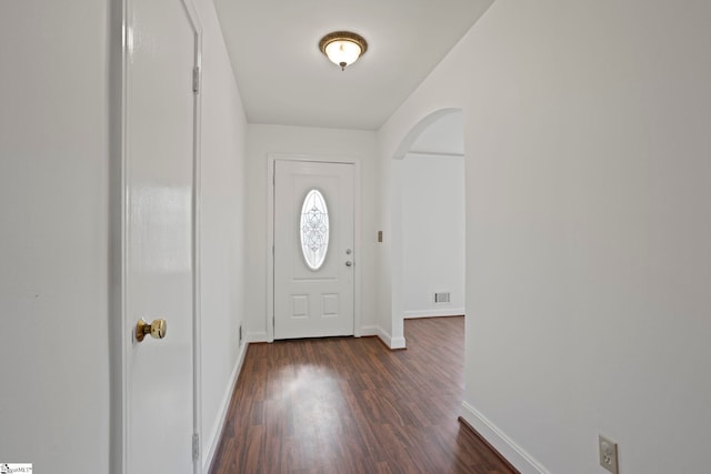 foyer featuring arched walkways, visible vents, dark wood finished floors, and baseboards