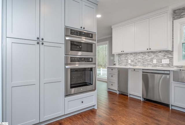 kitchen with tasteful backsplash, dark wood-type flooring, appliances with stainless steel finishes, and crown molding