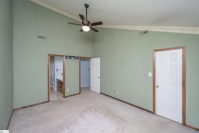 unfurnished bedroom with visible vents, light colored carpet, ensuite bathroom, and a textured ceiling