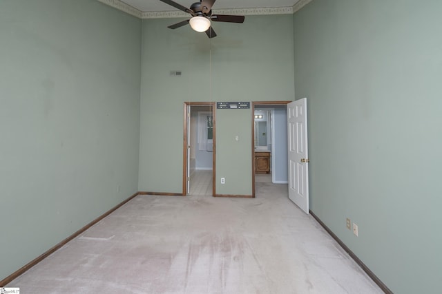 unfurnished bedroom featuring visible vents, ensuite bathroom, carpet flooring, baseboards, and a towering ceiling