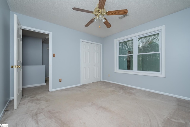 unfurnished bedroom featuring visible vents, baseboards, carpet floors, a closet, and a textured ceiling