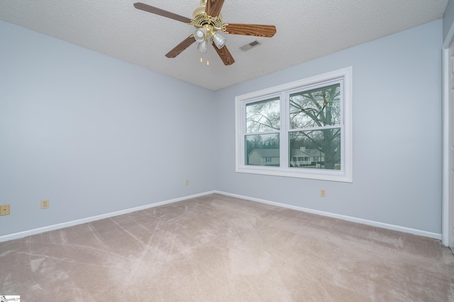 empty room with visible vents, light colored carpet, a textured ceiling, and baseboards