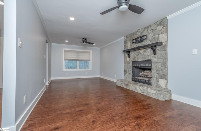 unfurnished living room with a stone fireplace, a ceiling fan, dark wood-style floors, and ornamental molding