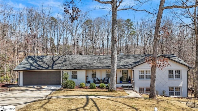 view of front of home with brick siding, a porch, a front yard, driveway, and an attached garage