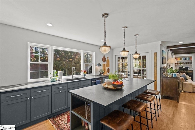 kitchen featuring gray cabinetry, a breakfast bar, light wood-style floors, and a sink