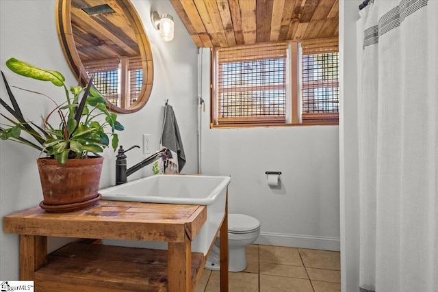 full bath featuring baseboards, toilet, wooden ceiling, tile patterned floors, and a sink