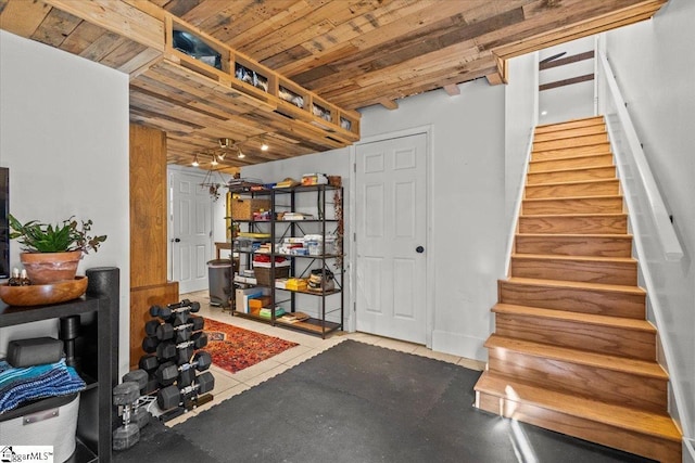 finished basement with tile patterned floors, stairway, and wood ceiling