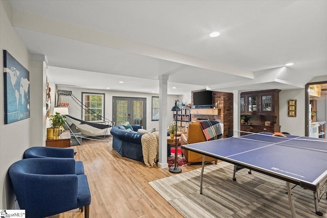 game room featuring wood finished floors, recessed lighting, a fireplace, and french doors