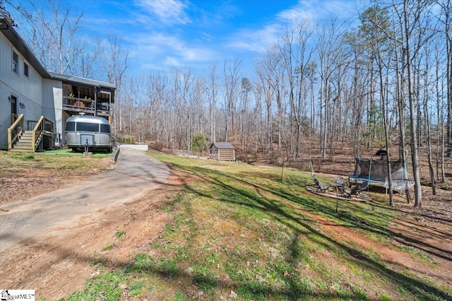 view of yard featuring an outdoor structure and a trampoline