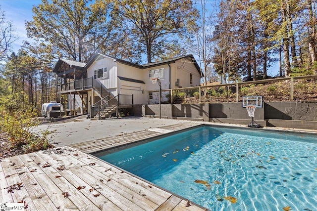 pool with a patio area, stairway, a deck, and fence