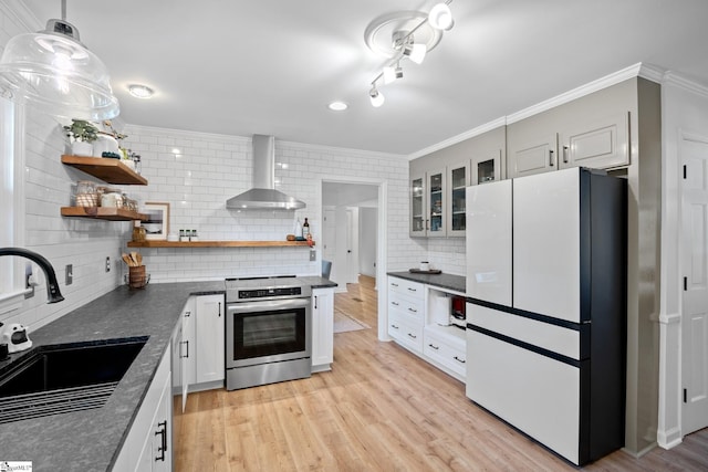 kitchen featuring open shelves, freestanding refrigerator, a sink, stainless steel range with electric stovetop, and wall chimney exhaust hood