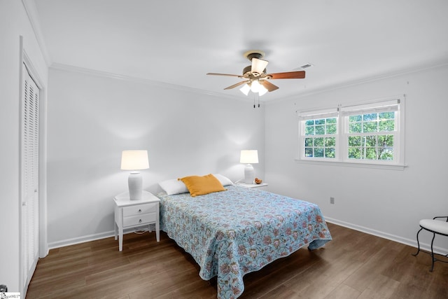 bedroom with visible vents, ornamental molding, wood finished floors, a closet, and baseboards