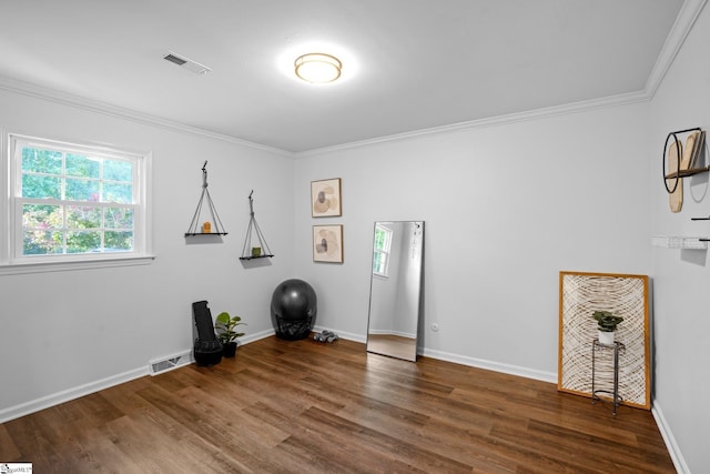 interior space featuring crown molding, wood finished floors, baseboards, and visible vents