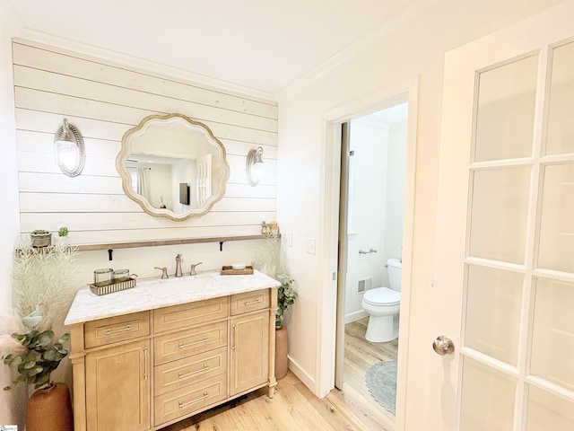 bathroom with visible vents, crown molding, toilet, wood finished floors, and vanity