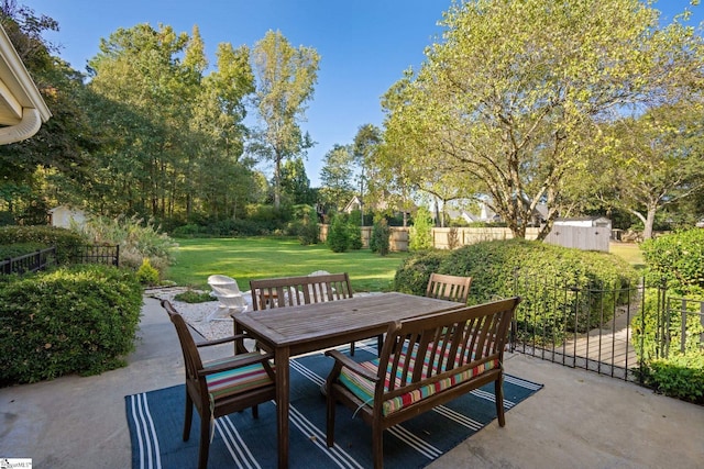 view of patio featuring an outdoor structure, outdoor dining space, a storage shed, and fence