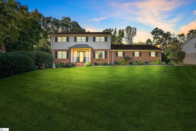 view of front of house with a yard and brick siding