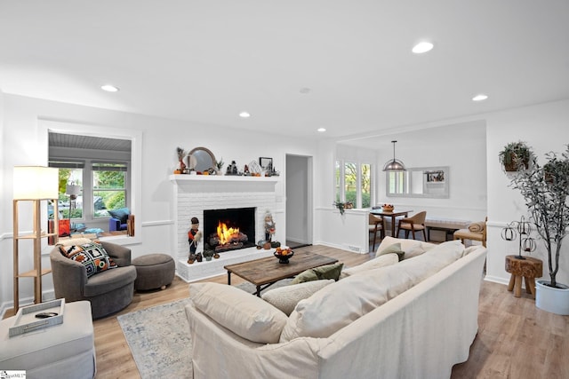 living room with a brick fireplace, plenty of natural light, recessed lighting, and light wood finished floors