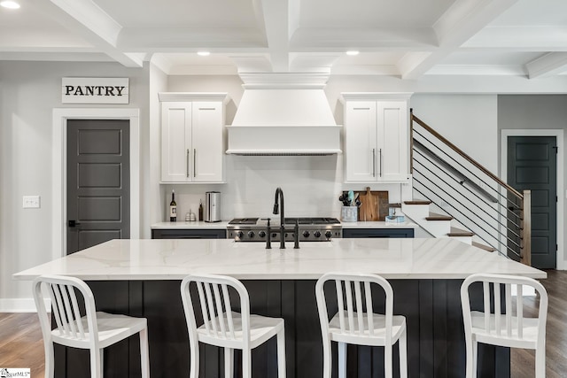 kitchen featuring premium range hood, dark wood finished floors, beam ceiling, light stone counters, and coffered ceiling