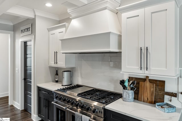 kitchen with dark wood-style floors, custom range hood, light stone counters, and double oven range